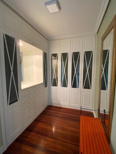 a walk in closet with white cabinets and a red rug at Chalet con Piscina Privada in Santander