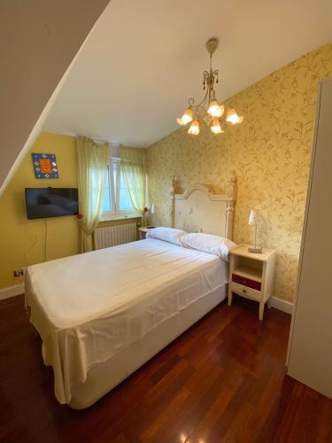 a bedroom with a large white bed and a chandelier at Chalet con Piscina Privada in Santander