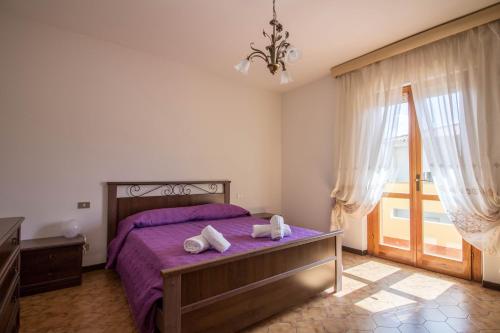 a bedroom with a purple bed with towels on it at Olbia - Comfy Apartment near the Airport! in Olbia