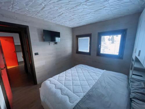 ein Schlafzimmer mit einem weißen Bett und einem Fernseher in der Unterkunft Biancaneve - 300 Metri dalle Piste, Free Parking e Wi-Fi in Passo del Tonale