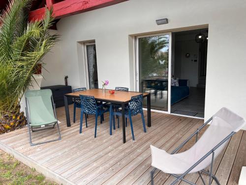 une terrasse en bois avec une table et des chaises dessus dans l'établissement La Cabosse, à Vieux-Boucau-les-Bains