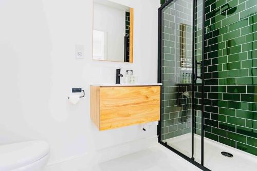 a bathroom with green tiles and a sink and a shower at Luxury Ocean Playroom SEA SALT CHALET in Barton on Sea