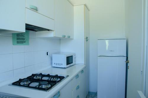 una cucina bianca con forno a microonde e piano cottura di Hotel Residence Villa San Giovanni a Portoferraio