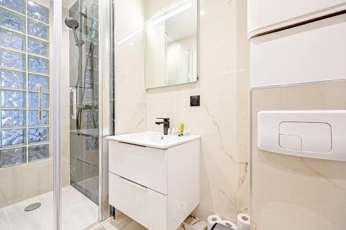 une salle de bain blanche avec un lavabo et une douche dans l'établissement Relax in a Stylish Flat in Montmartre, à Paris
