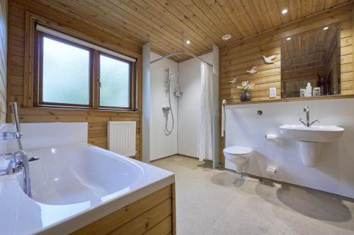 a bathroom with a tub and a toilet and a sink at Gadwall Lodge with Hot-tub in Carlisle