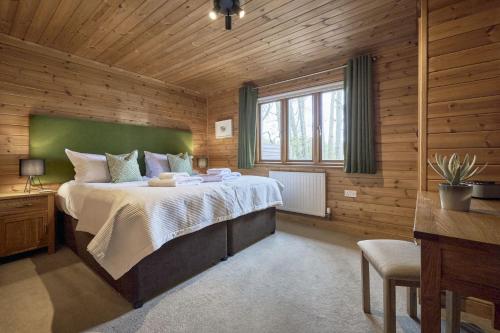 a bedroom with a large bed in a wooden room at Gadwall Lodge with Hot-tub in Carlisle