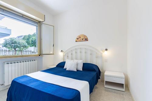 Un dormitorio con una cama azul y blanca y una ventana en Appartamento Turchese PT - MyHo Casa, en Alba Adriatica