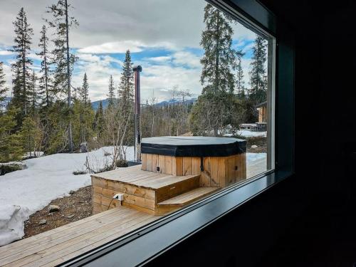 une fenêtre d'une chambre avec une baignoire en bois dans la neige dans l'établissement Cozy Mountain Cottage with beautiful views & Sauna, à Beitostøl