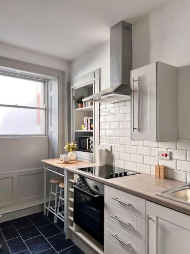 a white kitchen with a stove and a sink at Little Dockray One-Bed Apartment Centre of Penrith in Penrith