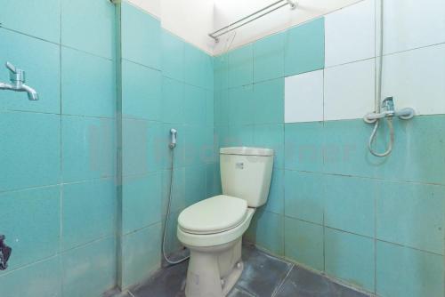 a bathroom with a toilet in a blue tiled wall at Wisma Alamanda near Terminal Cicaheum RedPartner in Bandung