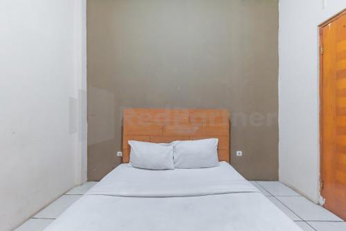 a bed with white sheets and pillows in a room at Wisma Alamanda near Terminal Cicaheum RedPartner in Bandung