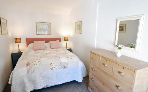 ein Schlafzimmer mit einem Bett mit einer Kommode und einem Fenster in der Unterkunft White Cottage Newport, Pembrokeshire in Newport