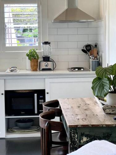 a kitchen with a counter with a microwave and a table at Gardeners' Cottage in Hamilton