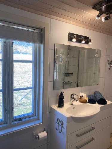 a bathroom with a sink and a mirror and a window at Unstad cabin with seaview in Unstad