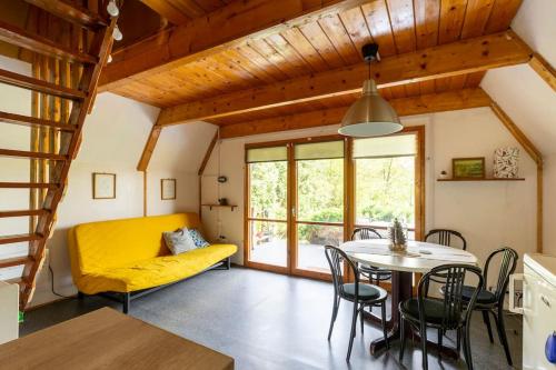 a living room with a yellow couch and a table at Bringás Vityilló - Nagymaros in Nagymaros