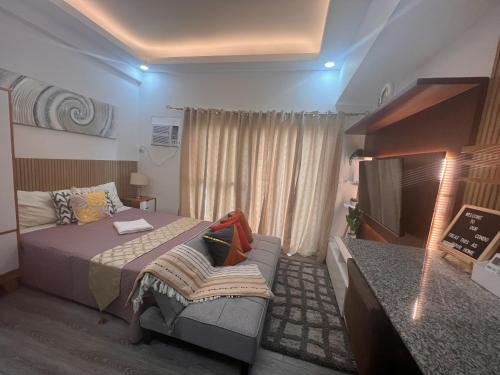 a bedroom with a bed and a couch and a television at Amani Grand Citygate at the back of Gaisano Milan in Davao City