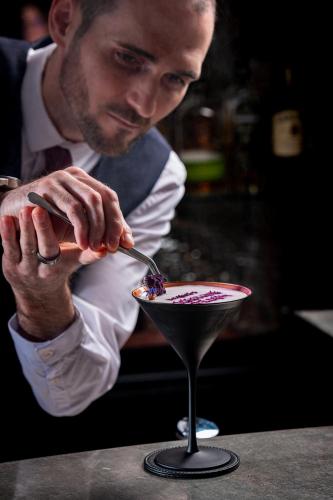 a man is stirring a drink in a martini glass at Hotel Bristol in Geneva