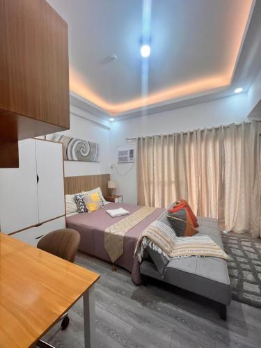 1 dormitorio con cama, escritorio y mesa en Amani Grand Citygate at the back of Gaisano Milan, en Davao City