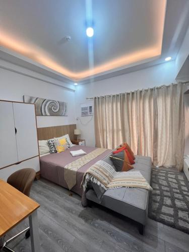 a bedroom with a bed and a table and a desk at Amani Grand Citygate at the back of Gaisano Milan in Davao City