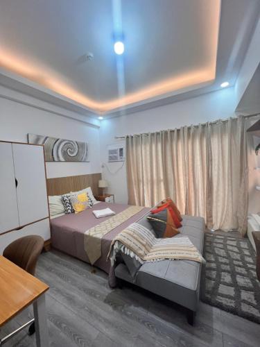 a bedroom with a bed and a table and a desk at Amani Grand Citygate at the back of Gaisano Milan in Davao City