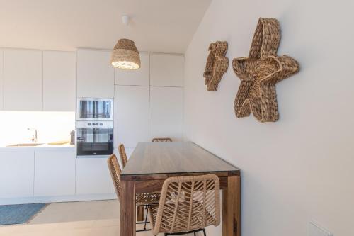 a kitchen with a table with chairs and someulptures on the wall at Casas do Forte Remos 5pax by Portugal hideaway in Cabanas de Tavira