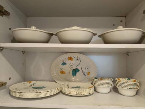 a shelf with bowls and plates in a closet at Mansha niwas - kahana home in Vrindāvan