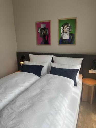 a bedroom with two white beds and pictures on the wall at INA Boutique Hannover-Linden - Digital Access in Hannover