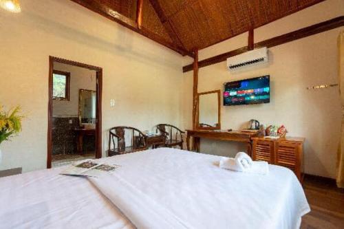 a bedroom with a white bed and a tv at Serene Resort Phú Quốc in Phu Quoc
