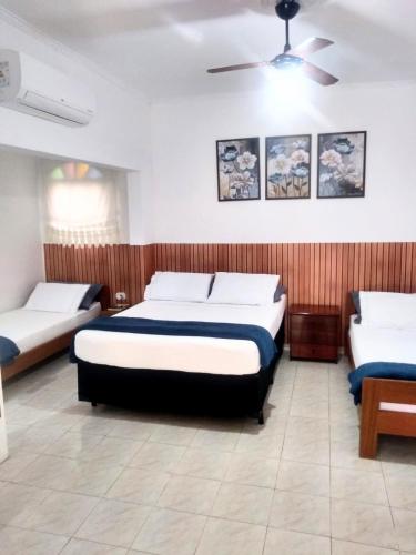 a bedroom with two beds and a ceiling fan at Pousada Rosa de Saron in Holambra