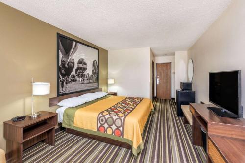 a hotel room with a bed and a flat screen tv at Super 8 by Wyndham Roswell in Roswell