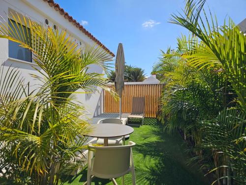 a patio with a table and chairs and palm trees at MAR BIANCO - Gay Men Only in Maspalomas