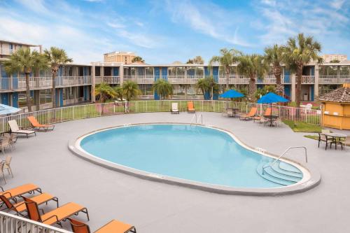 uma piscina com mobiliário de pátio e um resort em Howard Johnson by Wyndham Orlando-International Drive em Orlando