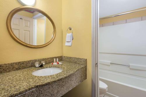 a bathroom with a sink and a mirror and a toilet at Howard Johnson by Wyndham Orlando-International Drive in Orlando