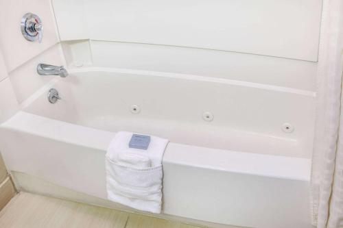a white bath tub with a towel on it at Hawthorn Suites Bloomington in Bloomington
