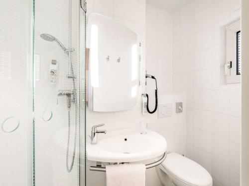 a white bathroom with a sink and a shower at ibis Hotel München City in Munich