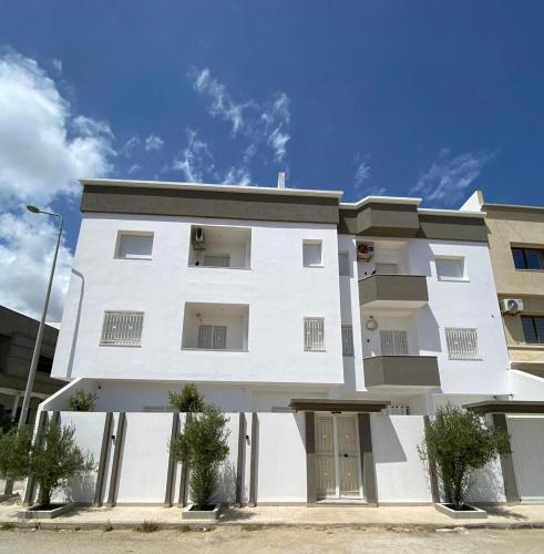 a white apartment building with a blue sky in the background at Dar Hella Apartments in El Maamoura
