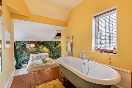 een grote badkamer met een bad en een bed bij Old School Cottage in Sandgate