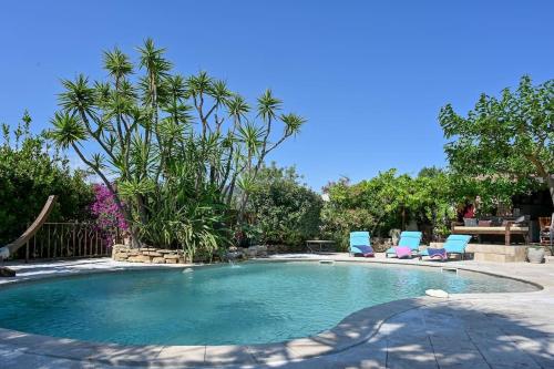 a swimming pool with two blue chairs and trees at Villa Provence au calme avec piscine in Toulon