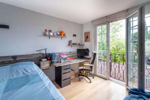 Schlafzimmer mit einem Bett und einem Schreibtisch mit einem Computer in der Unterkunft Villa Provence au calme avec piscine in Toulon