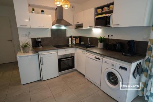 une cuisine avec des armoires blanches et une laveuse et une sécheuse dans l'établissement T2 climatisé avec WIFI et piscine, à Vias