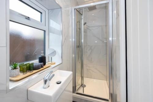 a white bathroom with a sink and a shower at Spacious & Modern 4-Bedroom Townhouse in Manchester