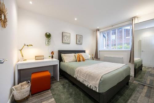 a bedroom with a bed and a desk and a window at Spacious & Modern 4-Bedroom Townhouse in Manchester