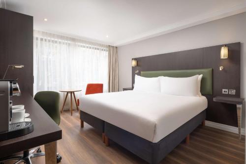 um quarto de hotel com uma cama grande e uma secretária em DoubleTree by Hilton London - Hyde Park em Londres