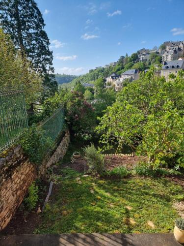 Un jardín con un muro de piedra y árboles. en Le Lumineux, en Rodez