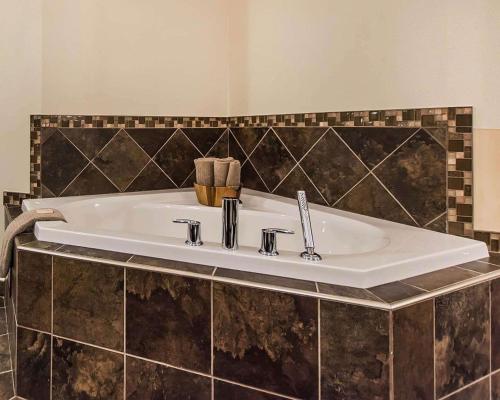 a white sink in a bathroom with black tiles at Quality Inn Moncton in Moncton