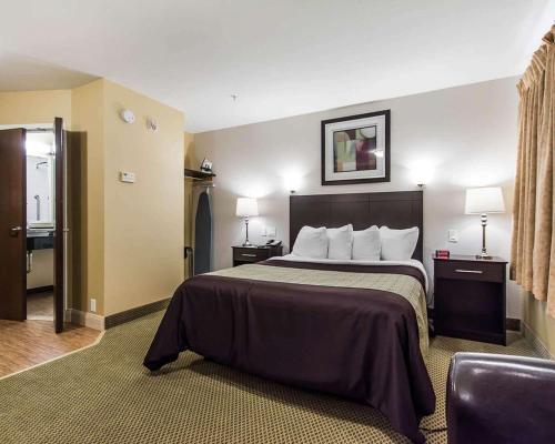 um quarto de hotel com uma cama grande e uma cadeira em Quality Inn Moncton em Moncton