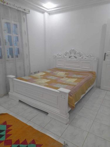a white bedroom with a bed in a room at Appartement yakine in Midoun