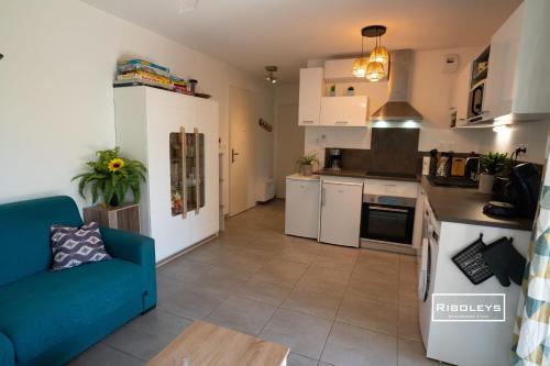 ein Wohnzimmer mit einem blauen Sofa und einer Küche in der Unterkunft T2 climatisé avec WIFI et piscine in Vias