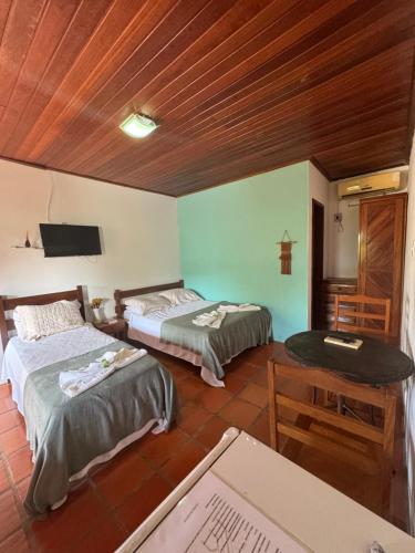 a room with two beds and a table and a table at Pousada Aláfia Sul in Una