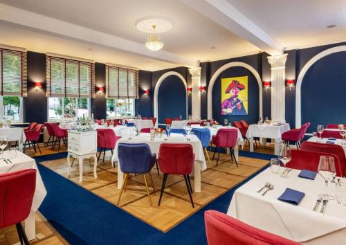 a restaurant with white tables and red chairs at Schlosshotel Rheinsberg in Rheinsberg